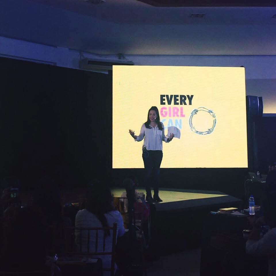 Victoria Herrera on stage speaking in front of a screen reading Every Girl Can